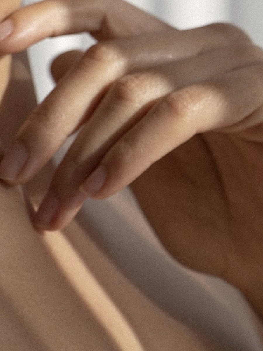 Le dita appoggiate sulla pelle, in luce radente